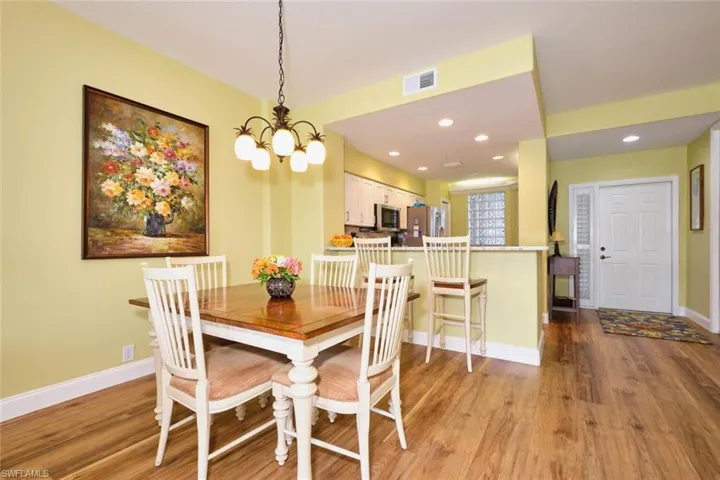 Dining room featuring visible vents, baseboards, wood finished floors, recessed lighting, and a notable chandelier