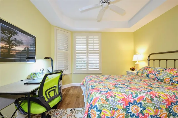 Bedroom featuring baseboards, ceiling fan, wood finished floors, and a raised ceiling