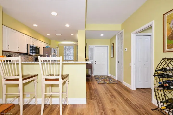 Kitchen featuring a peninsula, a kitchen bar, stainless steel appliances, wood finished floors, and white cabinetry