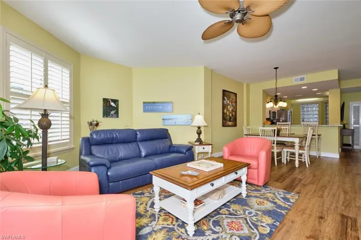 Living room featuring baseboards, visible vents, ceiling fan with notable chandelier, and wood finished floors