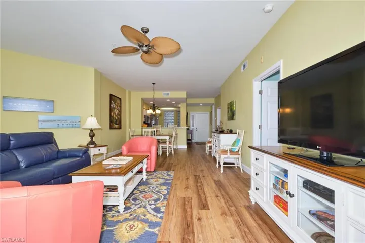 Living area with ceiling fan with notable chandelier, visible vents, wood finished floors, and baseboards