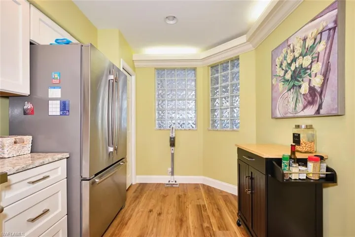Kitchen featuring freestanding refrigerator, white cabinets, baseboards, and light wood-type flooring