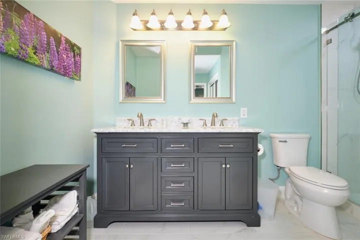 Bathroom featuring marble finish floor, a sink, toilet, and an enclosed shower
