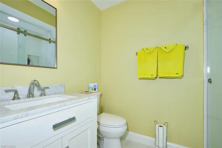 Bathroom featuring a stall shower, toilet, vanity, marble finish floor, and baseboards