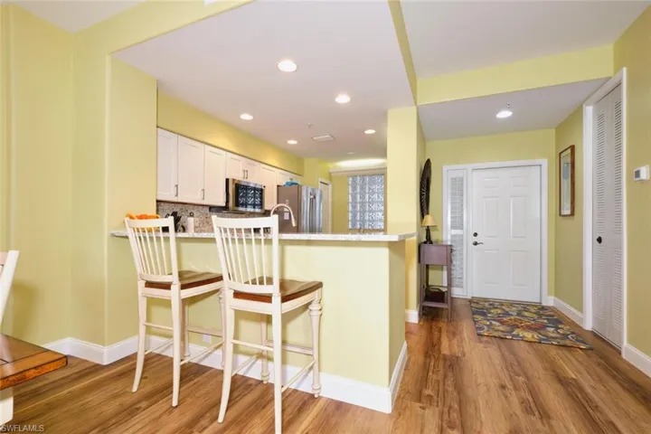 Kitchen featuring backsplash, wood finished floors, a kitchen bar, a peninsula, and stainless steel appliances