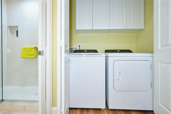 Laundry area featuring cabinet space, wood finished floors, and washer and clothes dryer