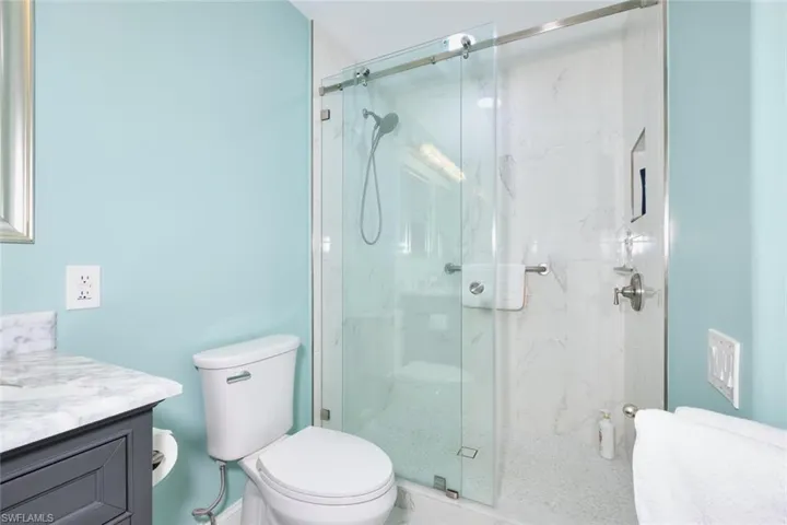 Bathroom featuring a marble finish shower, toilet, and vanity