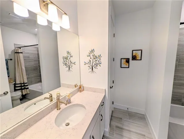 Full bathroom featuring shower / tub combo, vanity, and wood finish floors