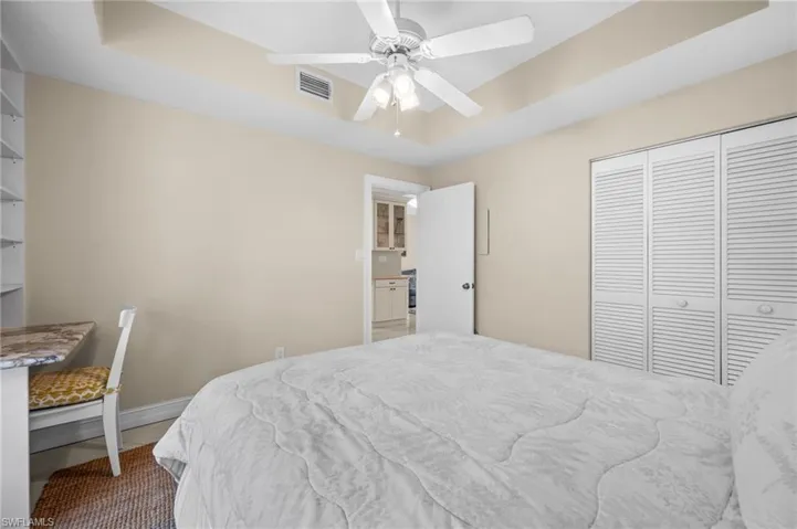 Bedroom featuring a raised ceiling, a ceiling fan, and a closet