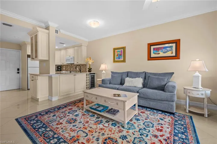 Living room with light tile patterned floors, ornamental molding, and ceiling fan