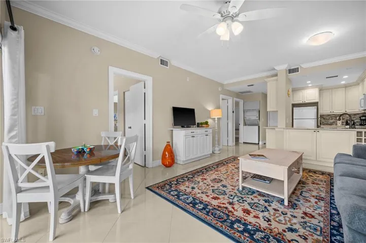Living room with crown molding, light tile patterned flooring, and a ceiling fan