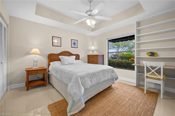 Bedroom with a raised ceiling, ceiling fan, and light tile patterned floors