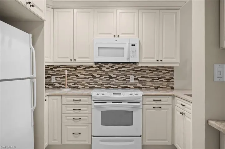 Kitchen featuring white appliances and white cabinets