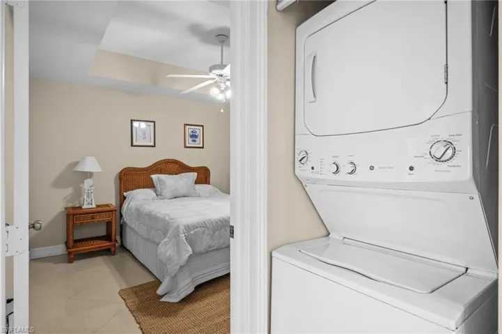 Washroom with tile patterned flooring, stacked washing machine and dryer, and a ceiling fan