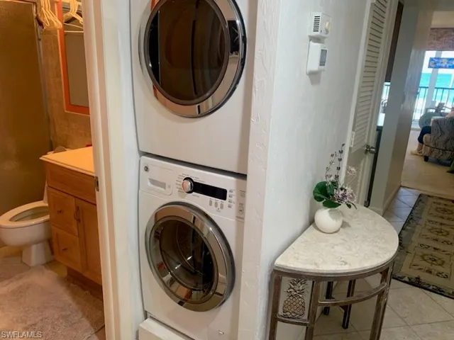 Laundry area with stacked washing maching and dryer and light tile patterned floors