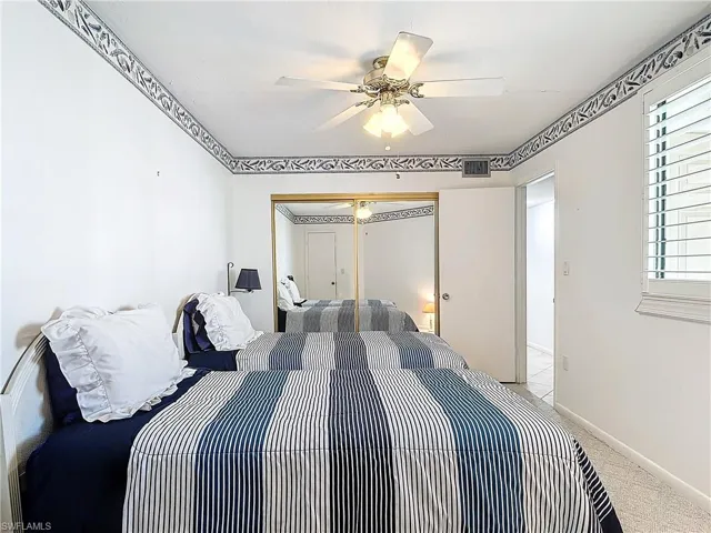 Carpeted bedroom featuring multiple windows, ceiling fan, and a closet