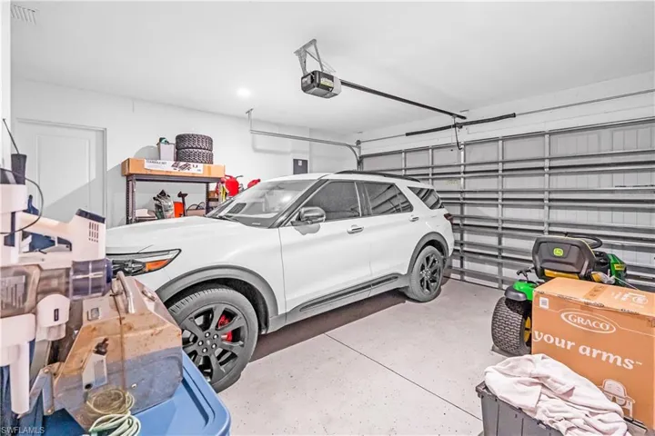 Spacious garage featuring a sectional overhead door, automatic opener, and a side access door
