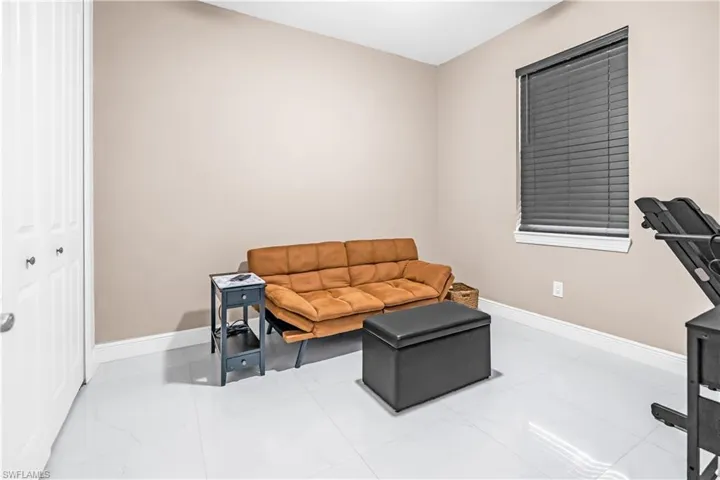 Bedroom #3 and or den with Neutral-toned walls complement the white baseboards and large format white tile flooring