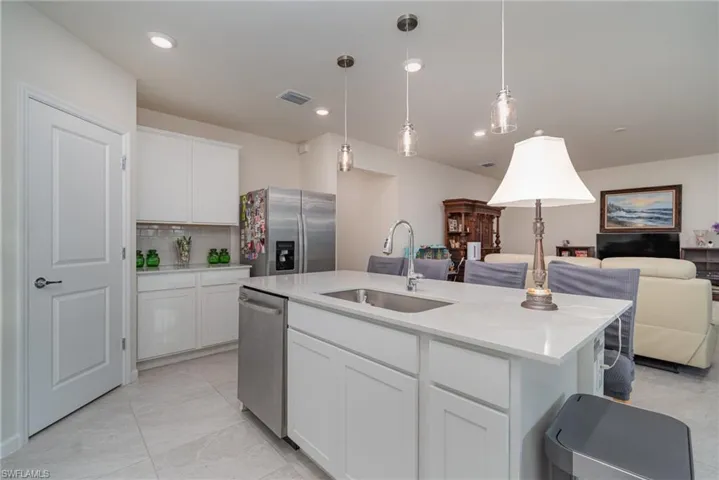 Kitchen featuring appliances with stainless steel finishes, backsplash, a kitchen island with sink, sink, and white cabinetry