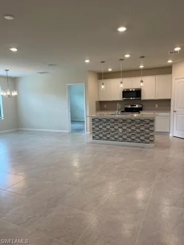 Kitchen with range, white cabinets, recessed lighting, open floor plan, and a notable chandelier