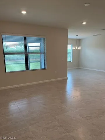Empty room featuring baseboards, a notable chandelier, and recessed lighting