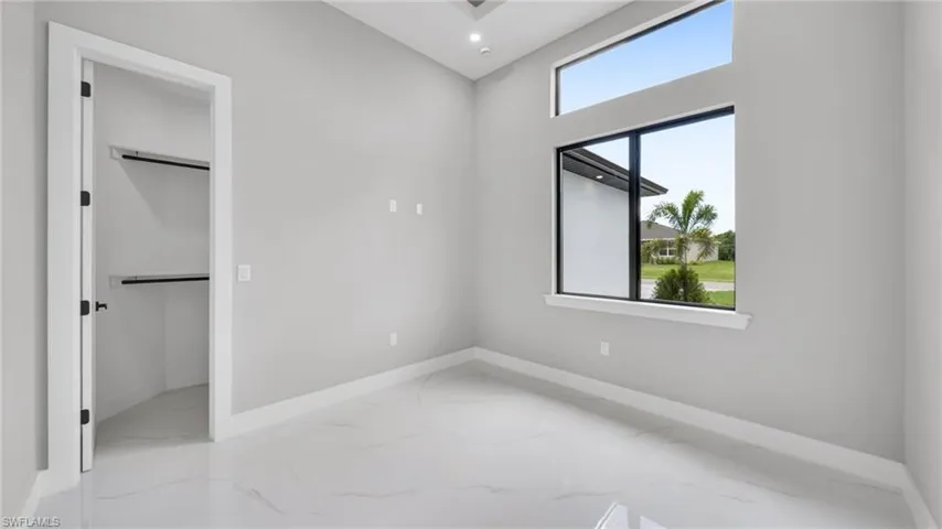Unfurnished bedroom featuring light marble finish floors, a spacious closet, and recessed lighting