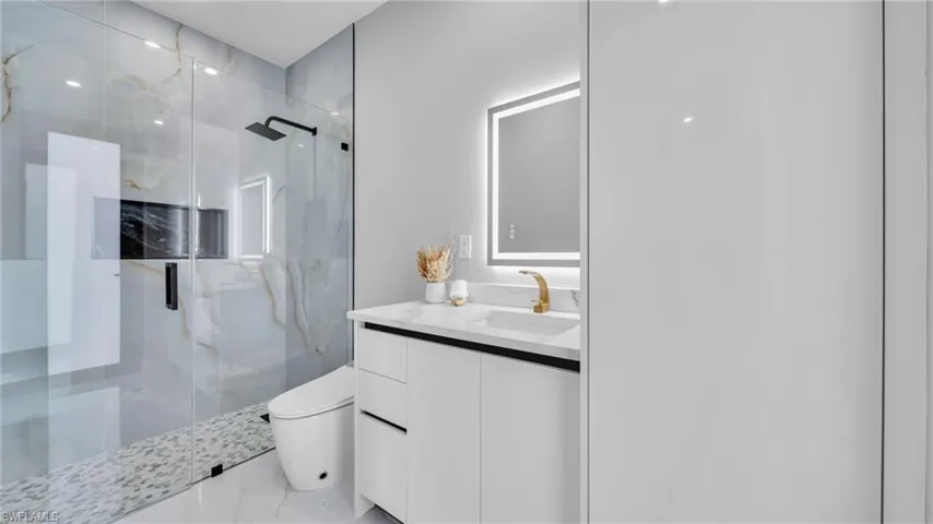 Bathroom featuring a marble finish shower, vanity, and marble finish floors