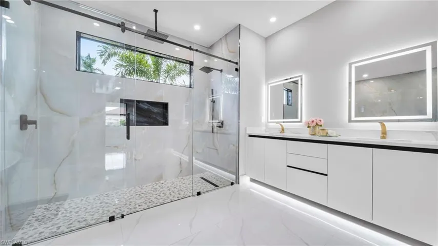 Bathroom with a marble finish shower, double vanity, marble finish flooring, and recessed lighting
