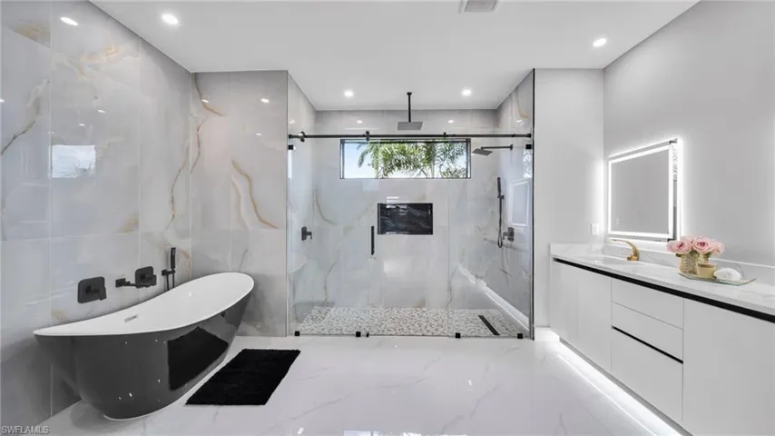 Full bathroom with a freestanding bath, light marble finish floors, a marble finish shower, vanity, and recessed lighting