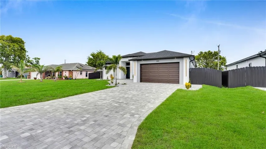 View of front facade featuring decorative driveway, a garage, and stucco siding