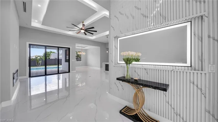 Corridor with marble tiled floors, a chandelier, a tray ceiling, and recessed lighting