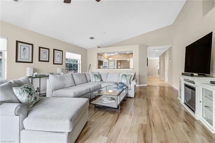 Living room featuring lofted ceiling, ceiling fan, and light wood-type flooring