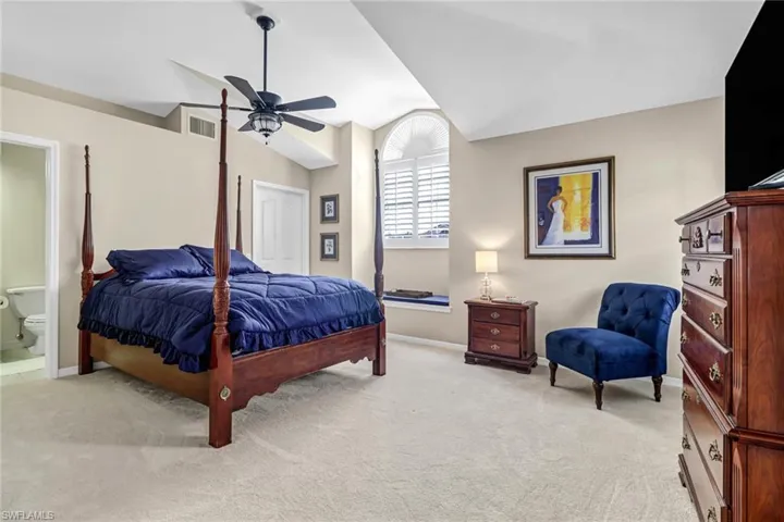 Bedroom featuring lofted ceiling, light colored carpet, ensuite bath, and ceiling fan