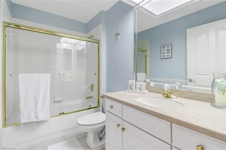 Full guest bathroom featuring tile patterned flooring, toilet, combined bath / shower with glass door, and vanity