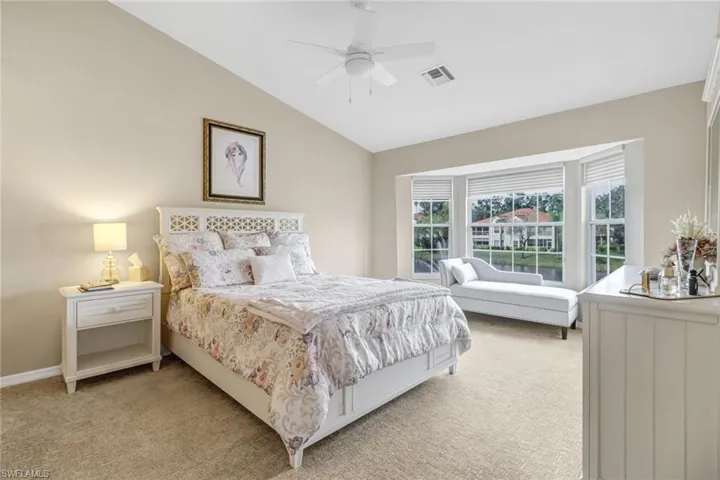 Primary bedroom with ceiling fan, vaulted ceiling, and multiple windows