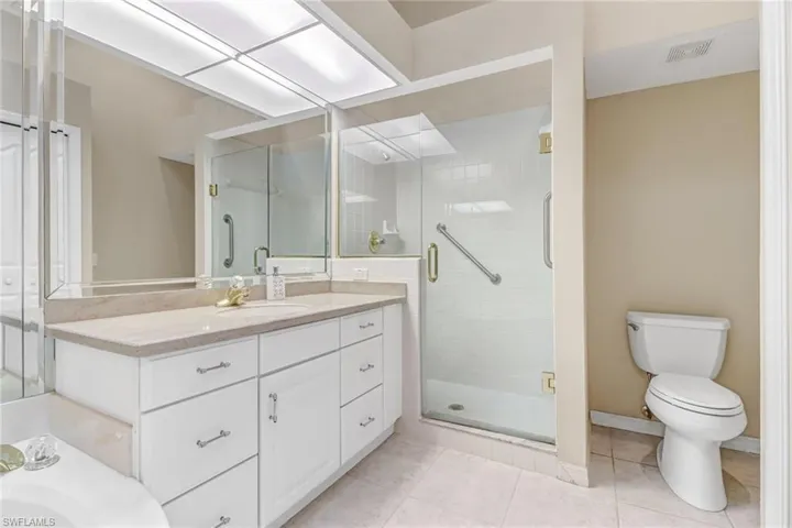 Primary Bathroom featuring tile patterned floors, walk in shower, toilet, and vanity