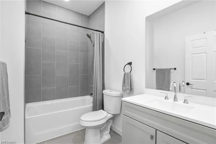 Bathroom with shower / bath combo, vanity, and light tile patterned floors