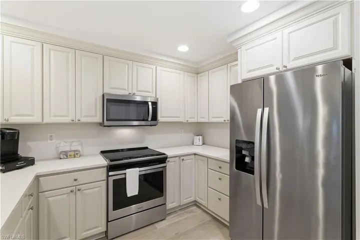 Kitchen with stainless steel appliances, light wood-style flooring, recessed lighting, and white cabinets