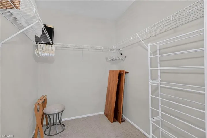 Walk-in storage space featuring neutral carpeting and extensive wire shelving systems with integrated vertical shoe storage