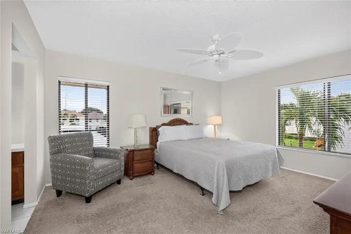 Bedroom featuring neutral wall paint, carpeting, a ceiling fan with integrated lighting, and large windows with horizontal blinds