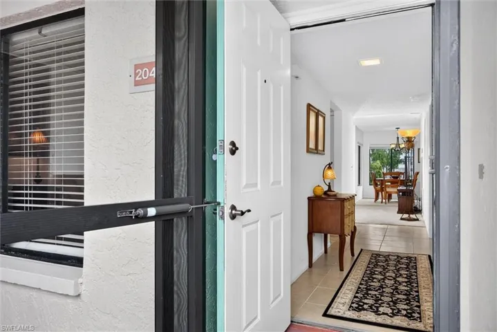 Entryway featuring a solid core door with a storm door, tile flooring, and recessed ceiling lighting