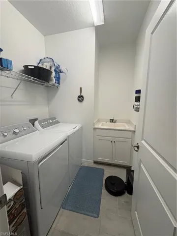 Laundry room with washing machine and clothes dryer, a textured ceiling, and light tile patterned floors