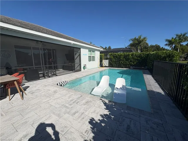 View of pool with a fenced backyard, a sunroom, and patio surround