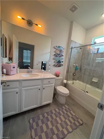 Bathroom featuring vanity, bath / shower combo with glass door, and ensuite bathroom