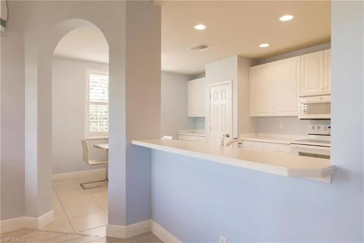Kitchen featuring white cabinets, white appliances, and light tile flooring