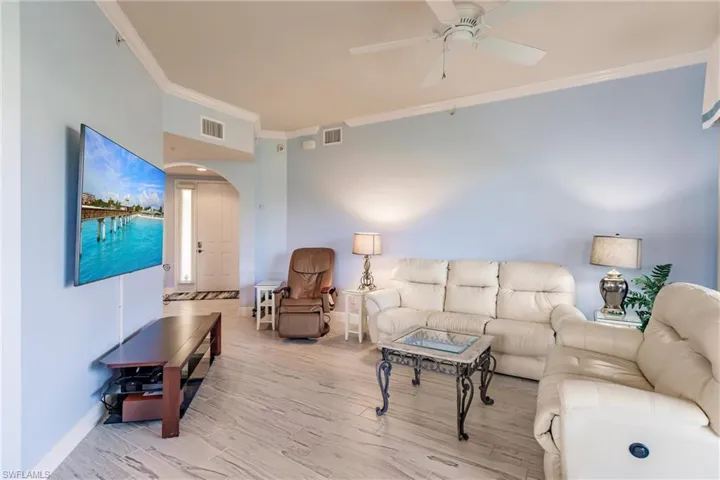Living room featuring ceiling fan, ornamental molding, and hardwood / wood-style flooring