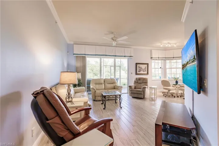 Living room with crown molding,hardwood / wood-style floors, ceiling fan, and rail lighting