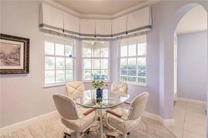 Tiled dining space featuring plenty of natural light and crown molding