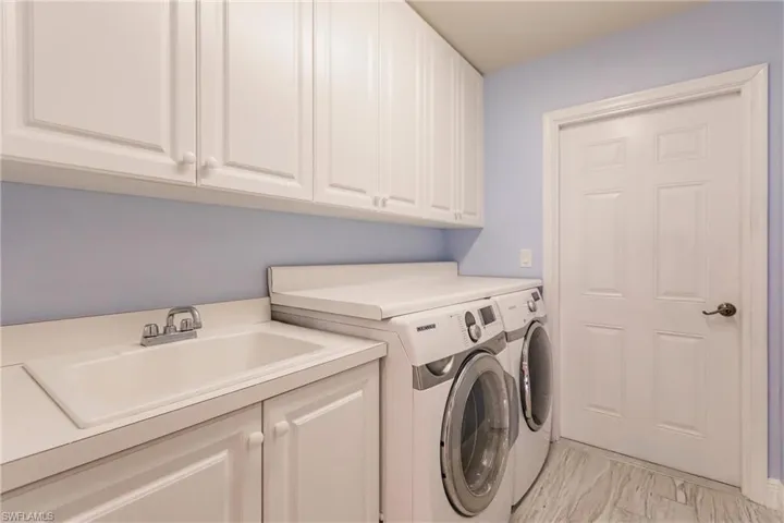 Utility area with Washer and Dryer featuring independent washer and dryer, sink, cabinets, and light tile floors