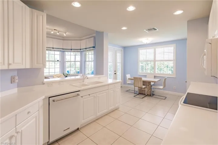 Kitchen featuring white dishwasher, white cabinetry, sink, and a healthy amount of sunlight